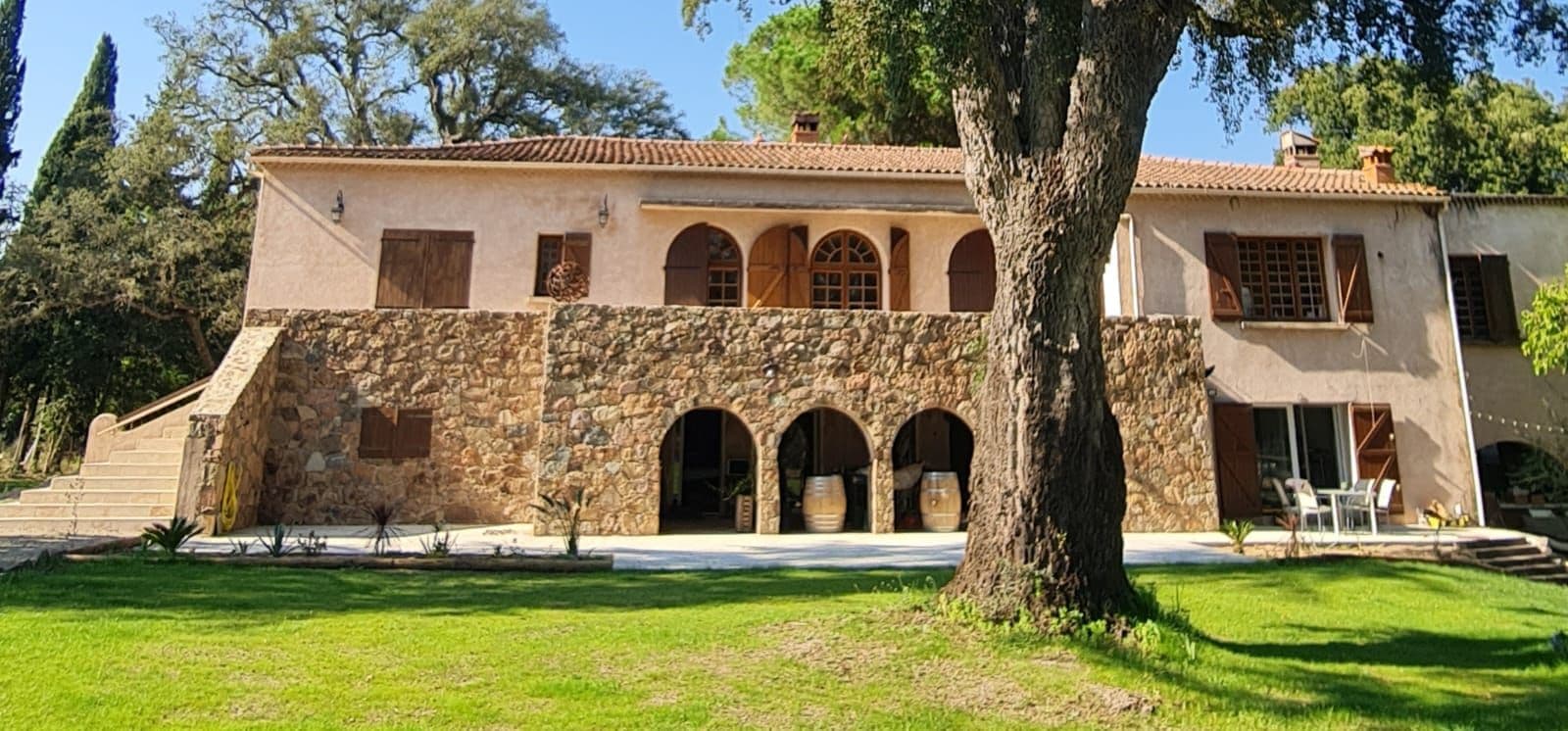 Le mas en pierre et la pelouse arborée du Domaine A FONTE